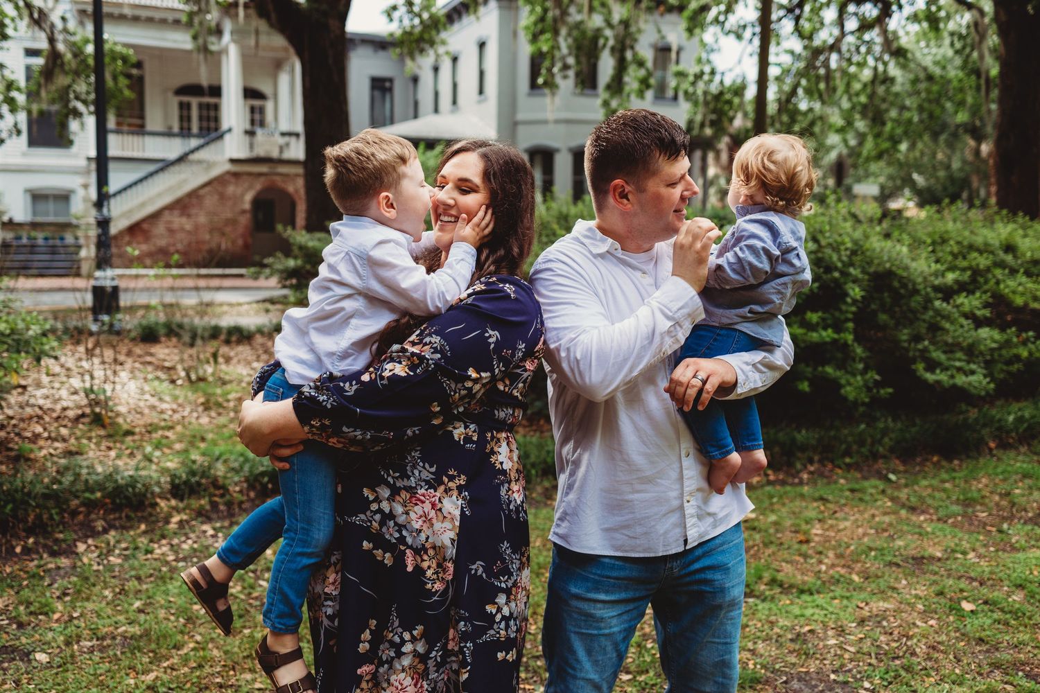 A family shares tender moments together in an outdoor garden setting during a photo session.