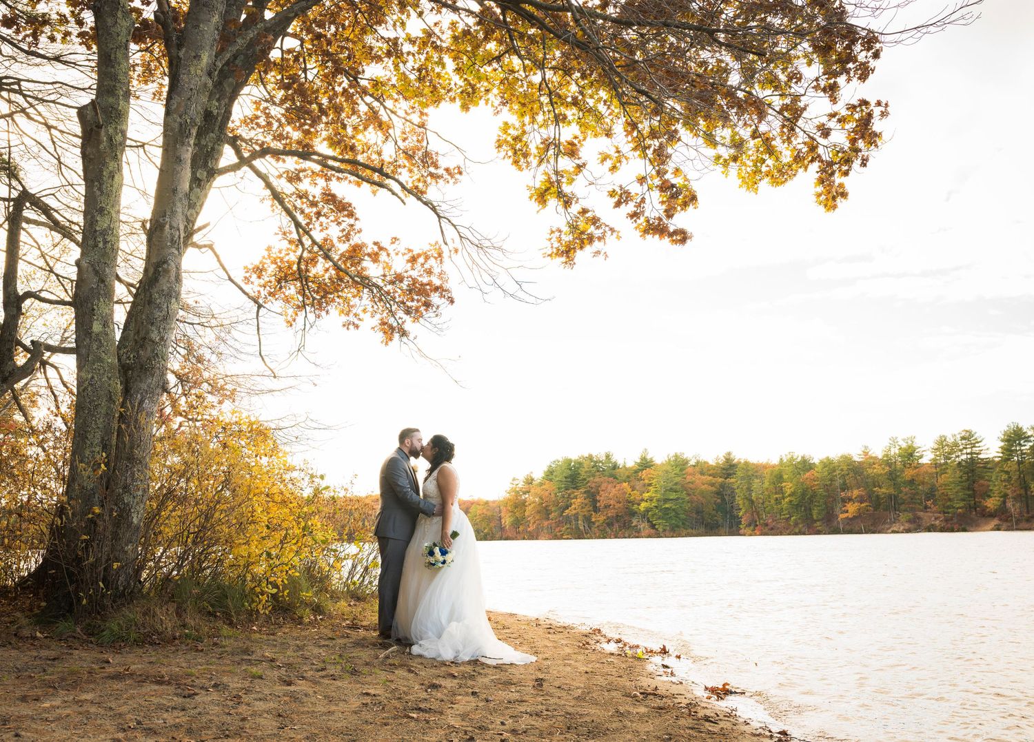 Romantic silhouettes of couples embracing by a lake during golden hour with autumn trees in the background.