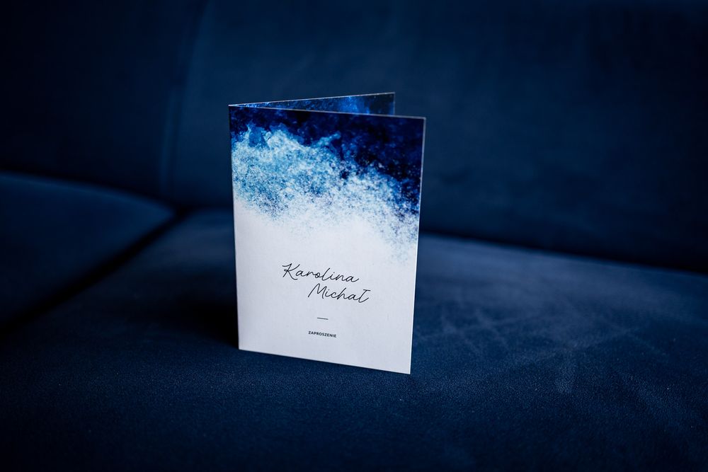 Wedding invitation cards arranged on dark blue background with dramatic lighting.