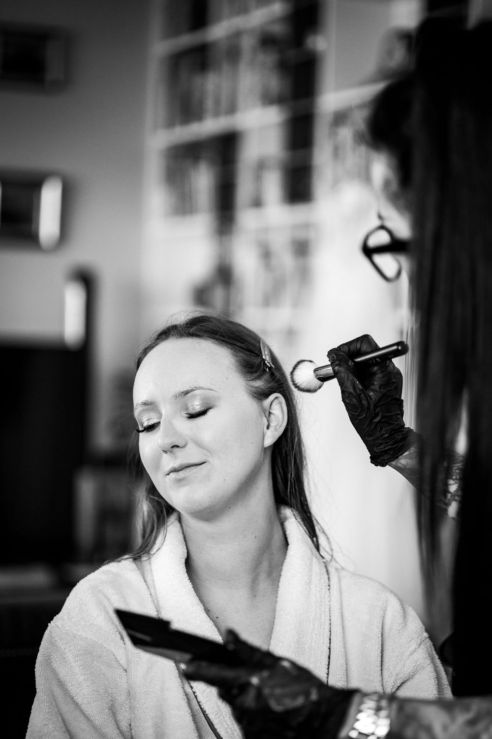 Getting ready scene with makeup application in black and white photography.