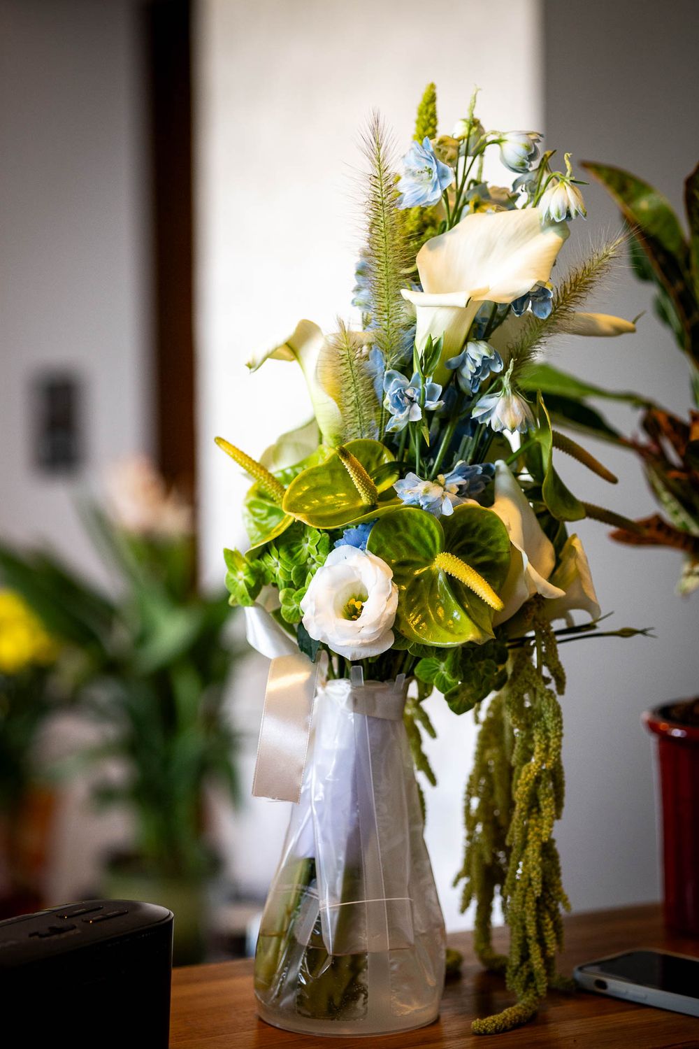 White and blue floral arrangement in glass vase with delicate greenery.