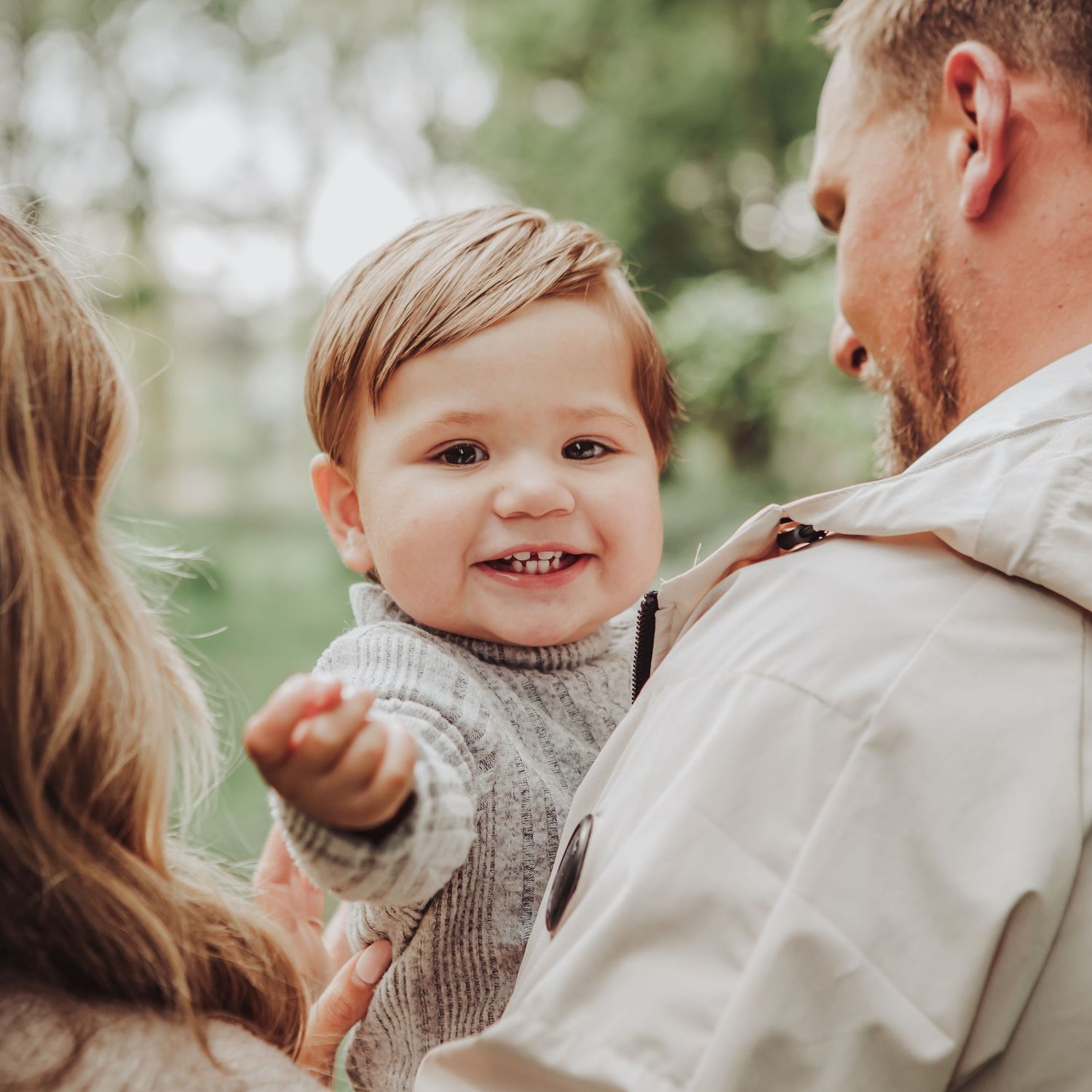 Young boy smiling at the camera with his parents.