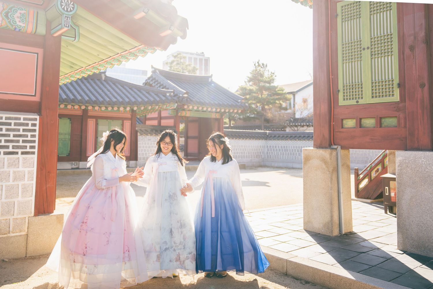 Traditional Korean hanbok-wearing couple poses together in front of historic palace architecture.