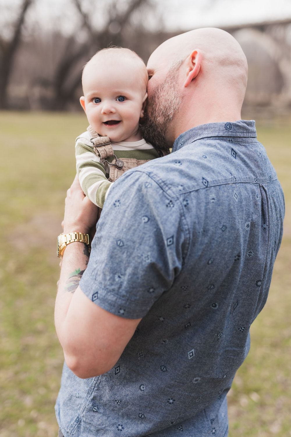 Sweet outdoor family moment with a baby in casual wear being held against denim clothing.