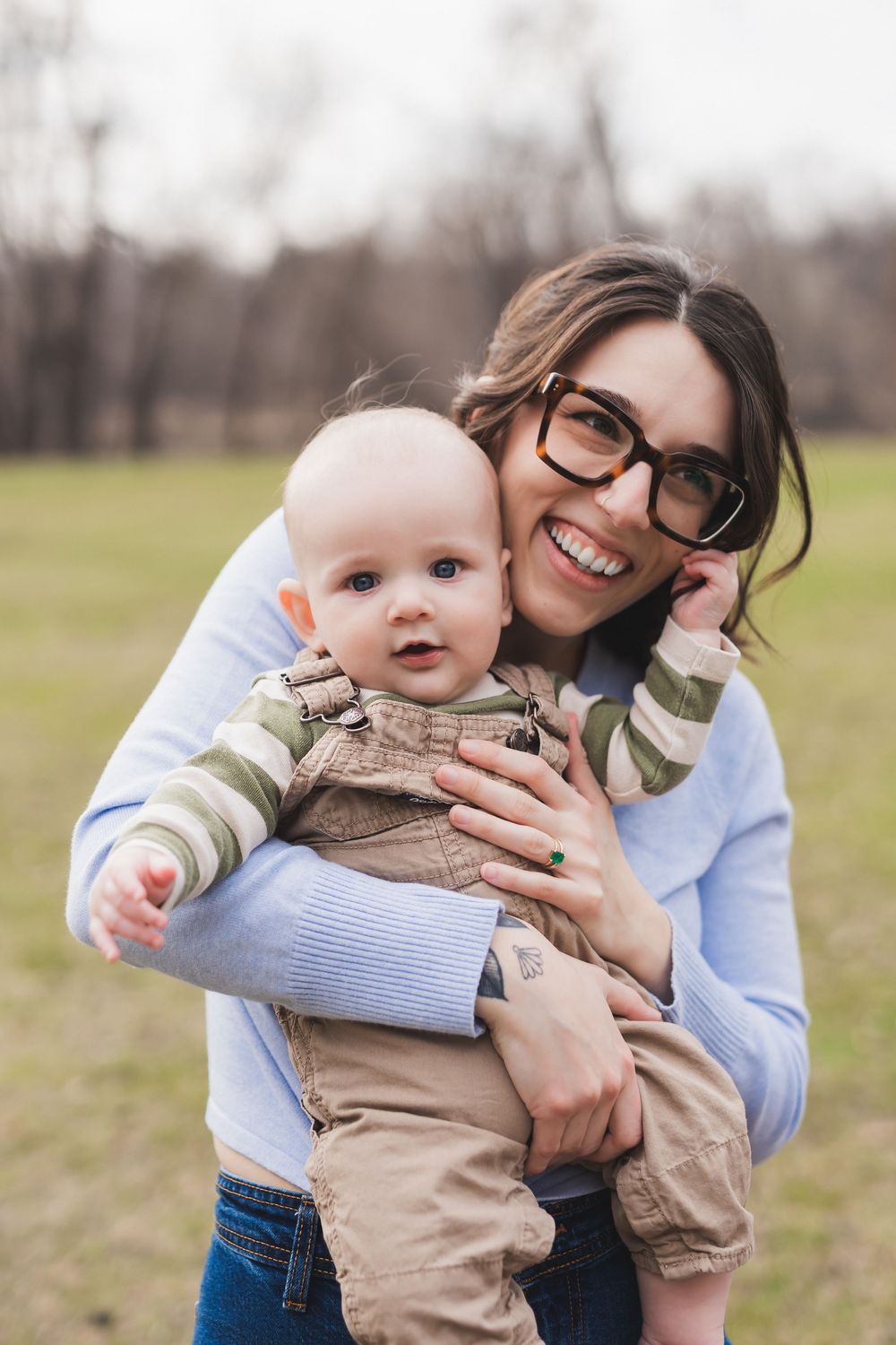 Joyful playtime outdoors with baby in khaki outfit and parent in blue sweater sharing sweet moments together.