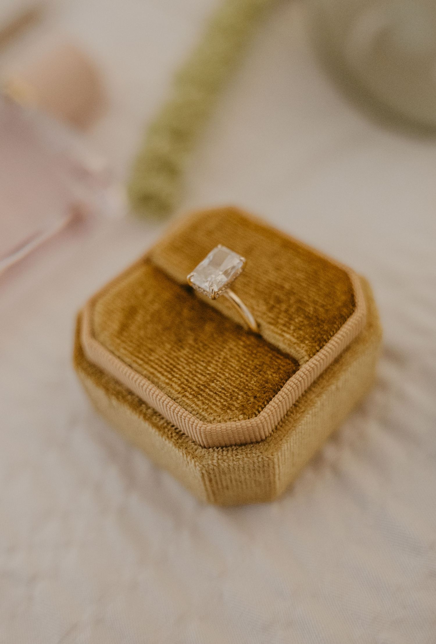 Close-up sequence showing wedding rings being placed on a tan velvet ring box cushion.