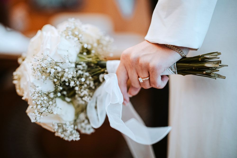 A row of hands holding delicate white baby's breath flower bouquets against a warm background.