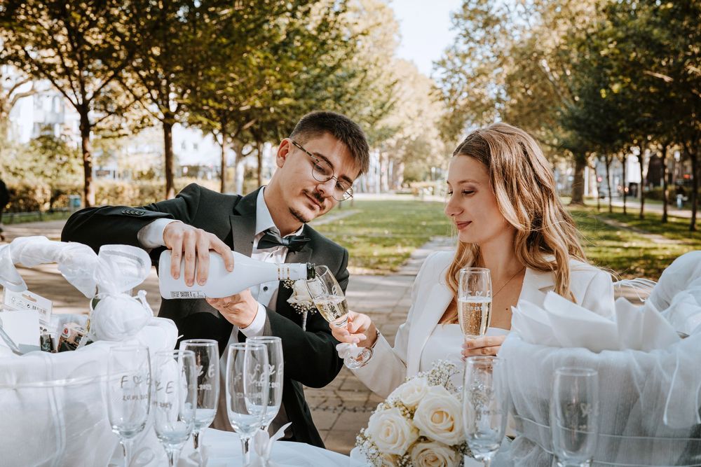 Elegant wedding celebration scene with champagne toasts and white floral decor at an outdoor reception.