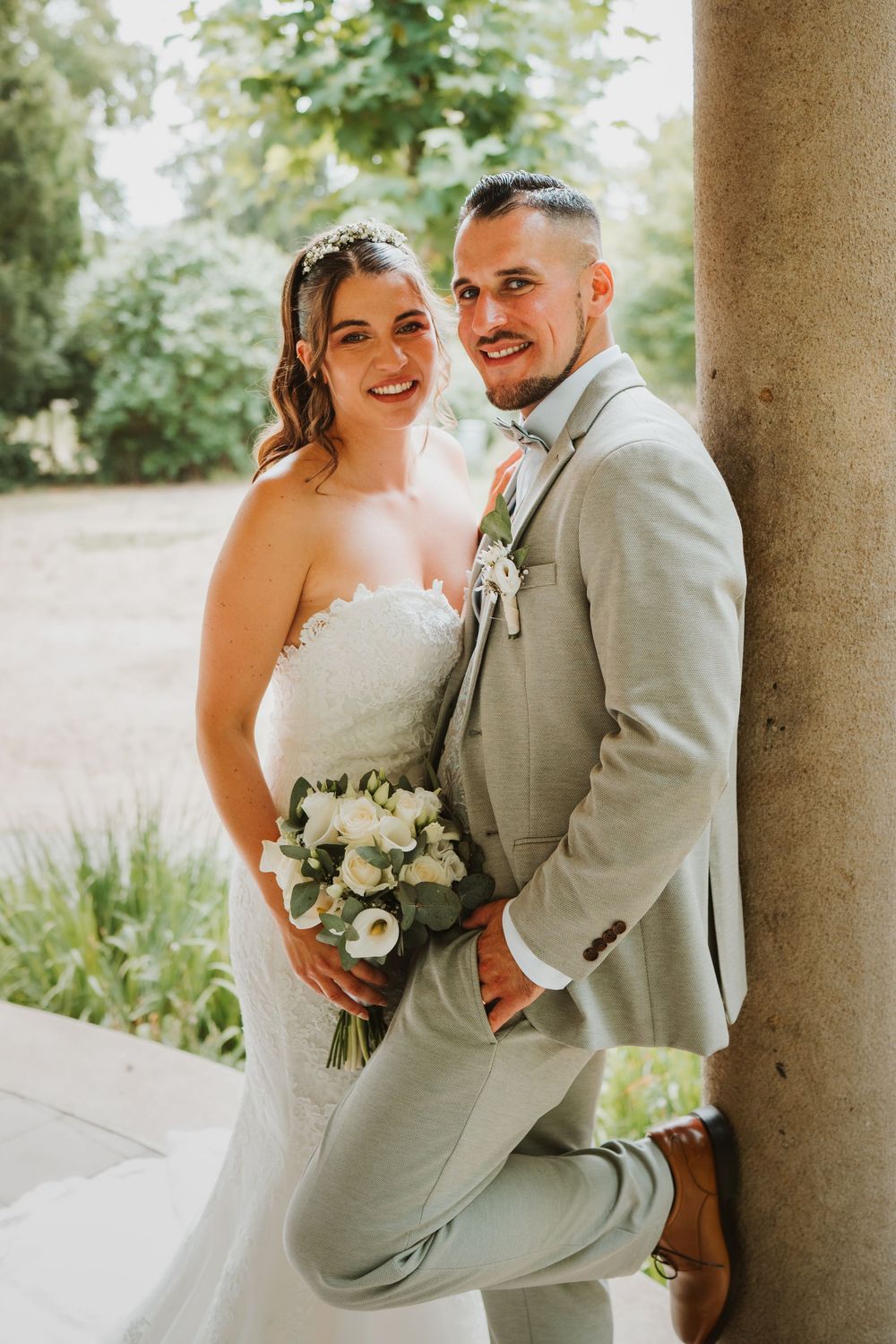 A romantic wedding couple shares intimate moments under stone pillars in a series of candid photographs.