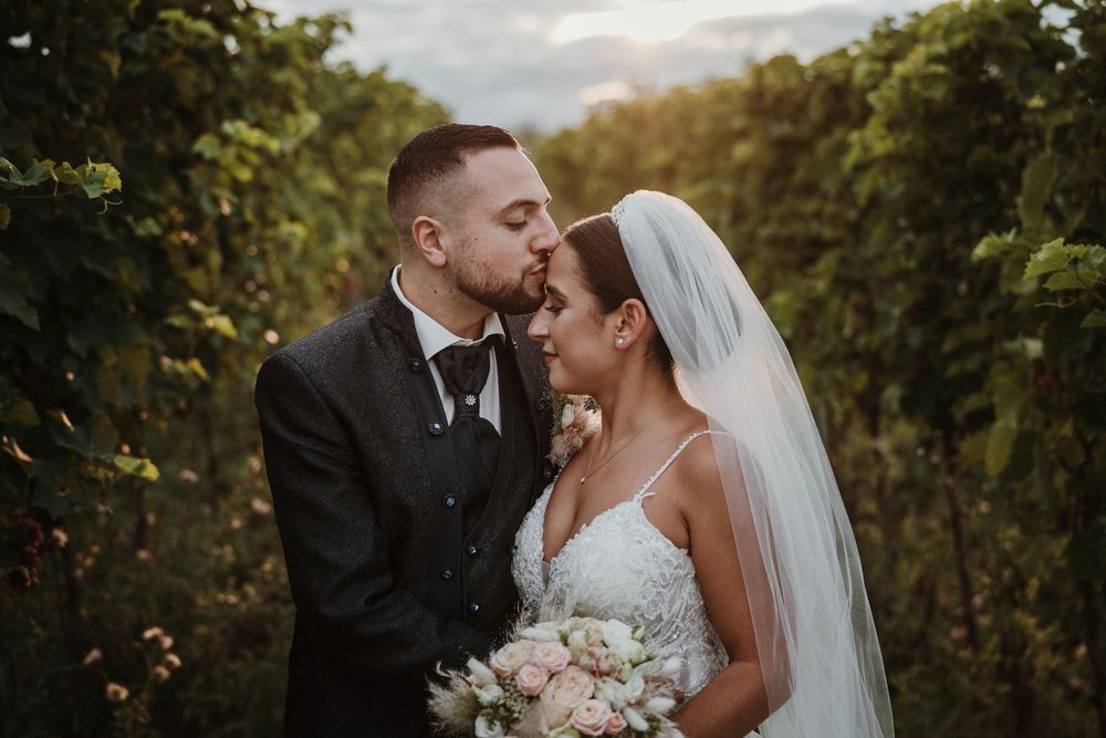 A romantic wedding couple embraces in a lush garden setting during golden hour sunset.