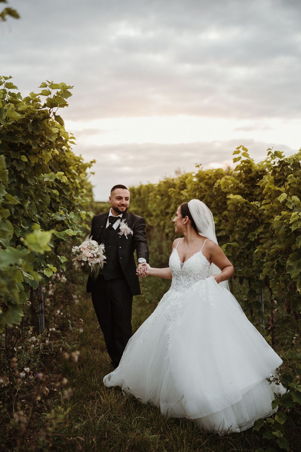 A romantic wedding photoshoot in a scenic vineyard at sunset with a flowing white ballgown dress.