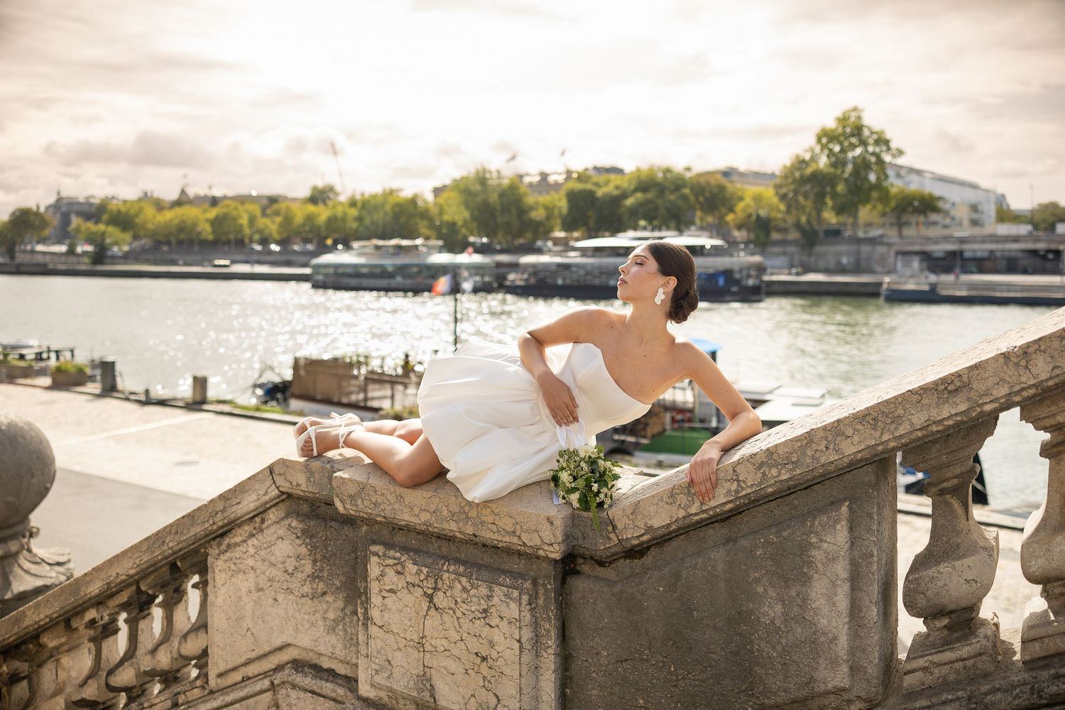 Wedding photos taken along a scenic waterfront with stone balustrades and city views.