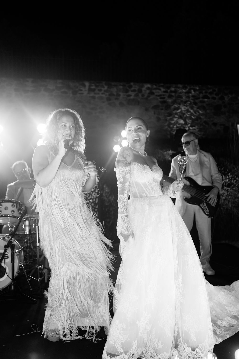 Multiple people in flowing white dresses dance together in a dimly lit space during what appears to be a performance.