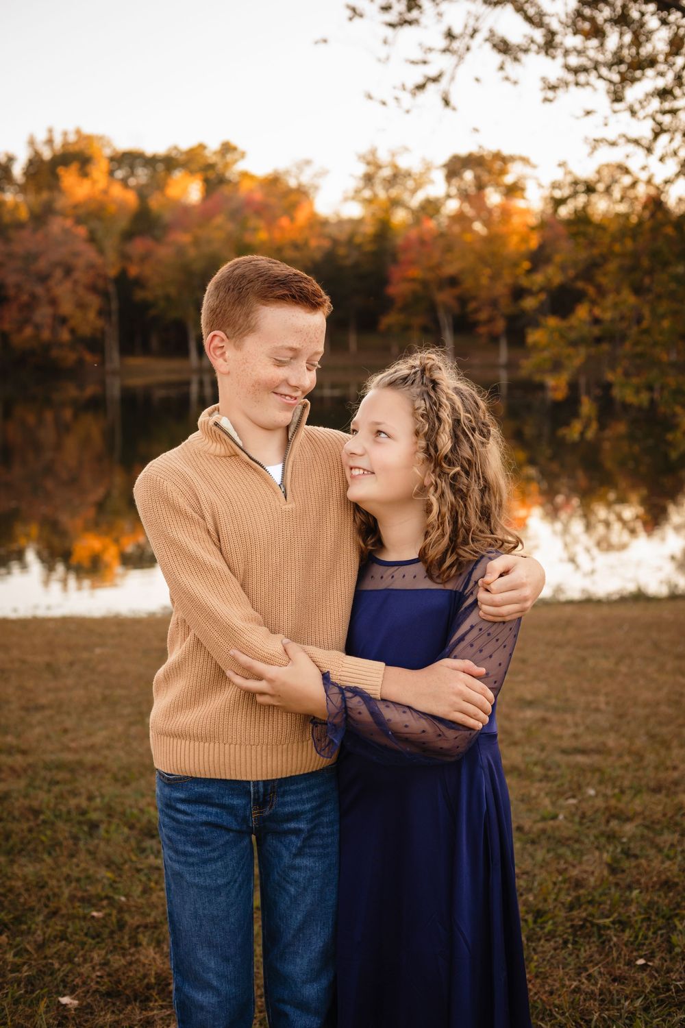 Brother and sister hug and smile at each other against a rich, warm autumn nature backdrop, captured by Charlottesville family photographer.