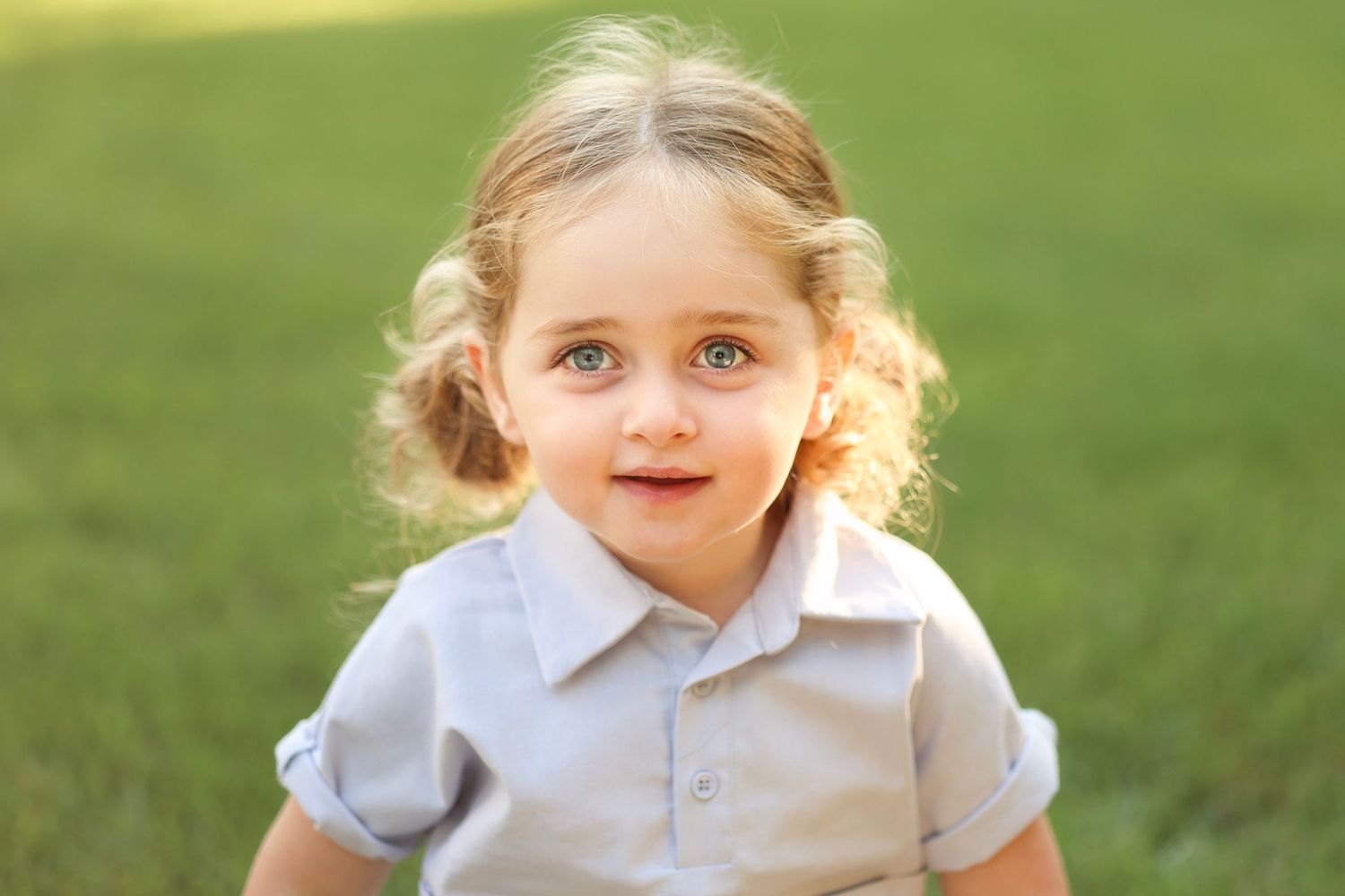 close up of upsherin boy with the sun highlighting his blond pigtails