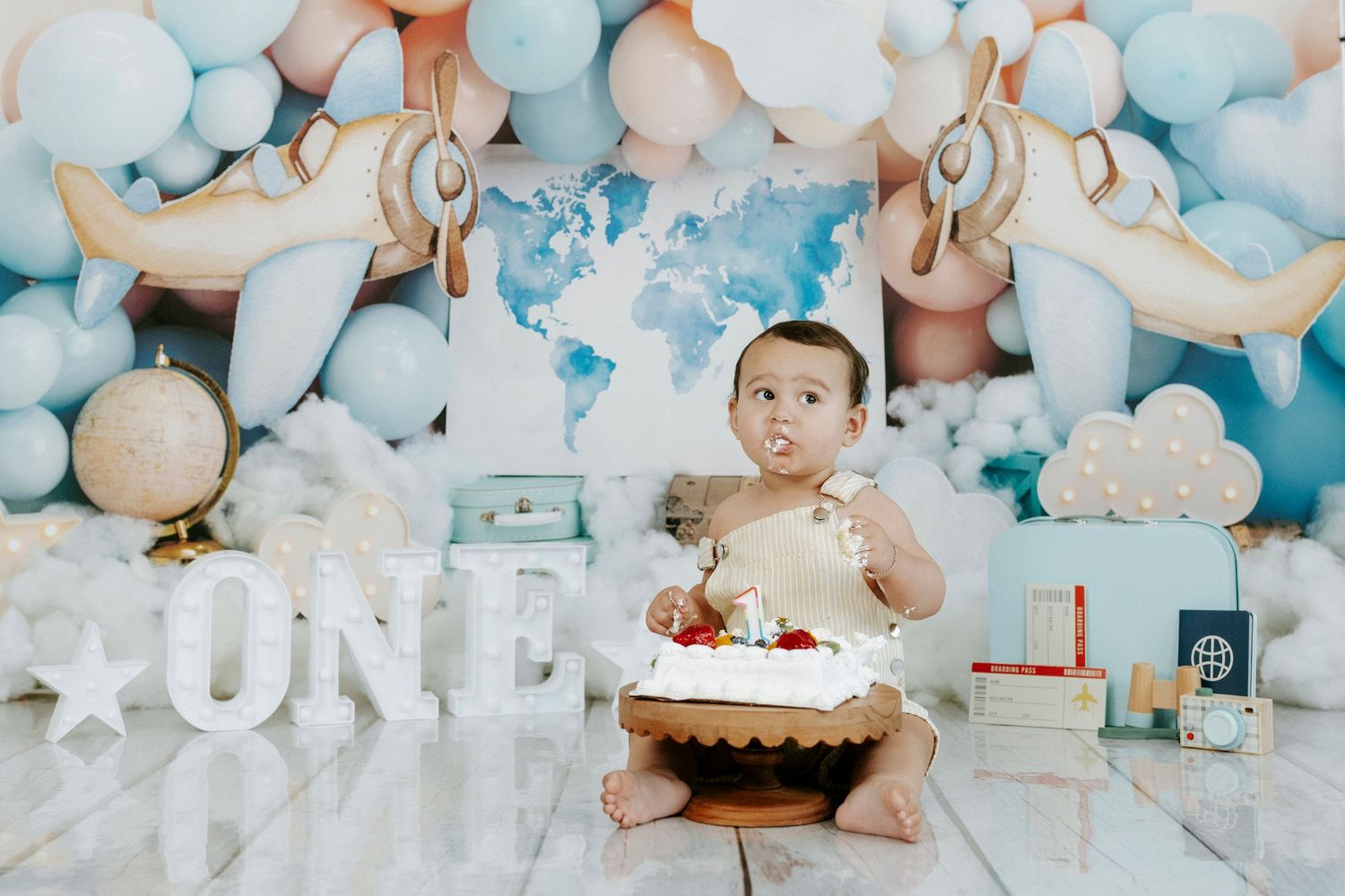 A blue and white themed first birthday party setup with balloons, cake, and decorative elements.