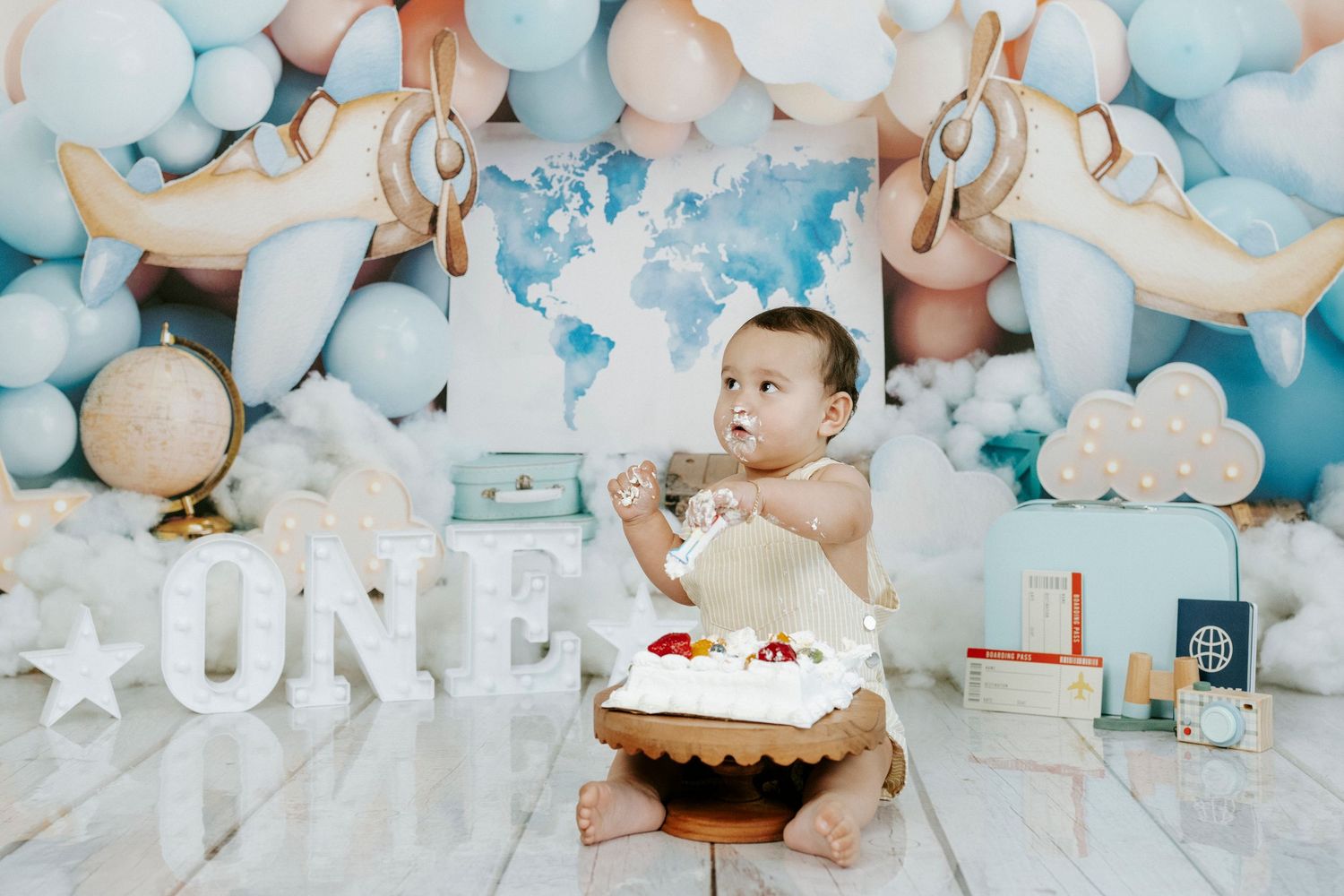 Baby's first birthday celebration with blue and white balloon arch, cake smash setup and 'ONE' lettering decoration.