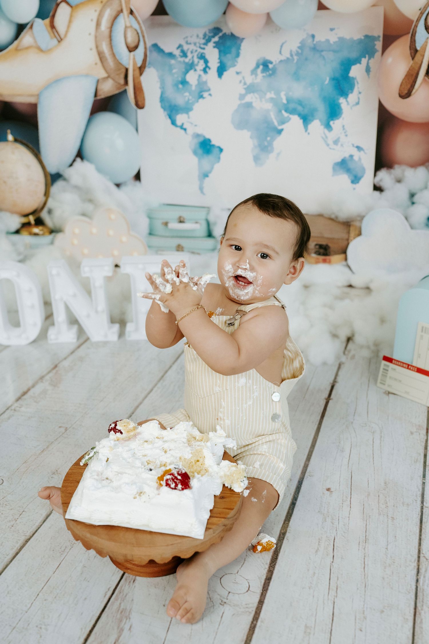 A cake smash photo session setup with blue and white balloons on a rustic wooden floor.