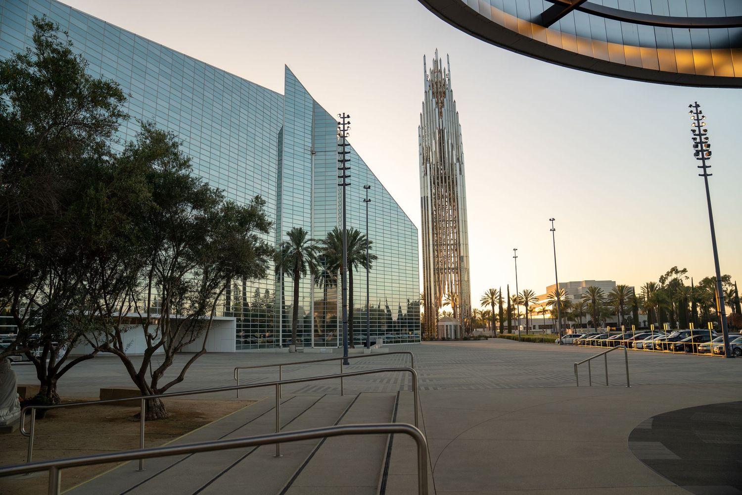 Modern glass building exterior with curved architecture at sunset.