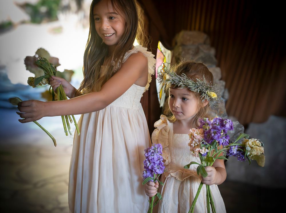 A series of candid wedding moments showing flower girls in white dresses holding bouquets at an indoor venue.
