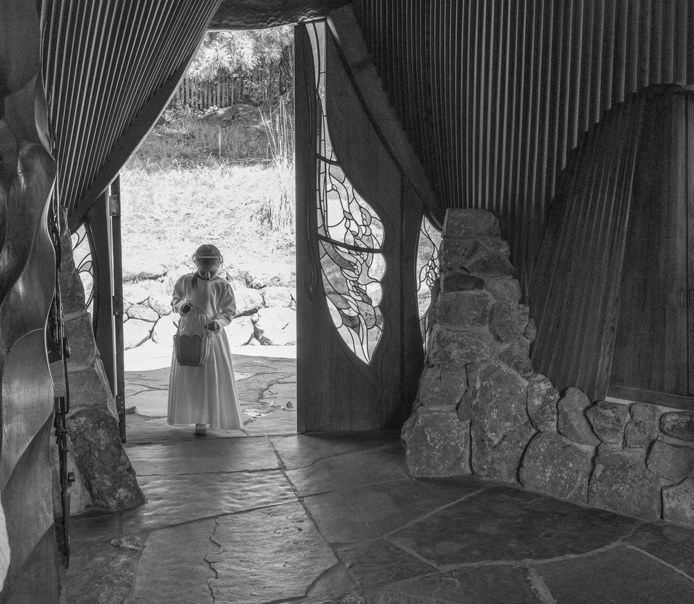 A silhouetted figure stands in a stone archway creating a dramatic architectural frame.
