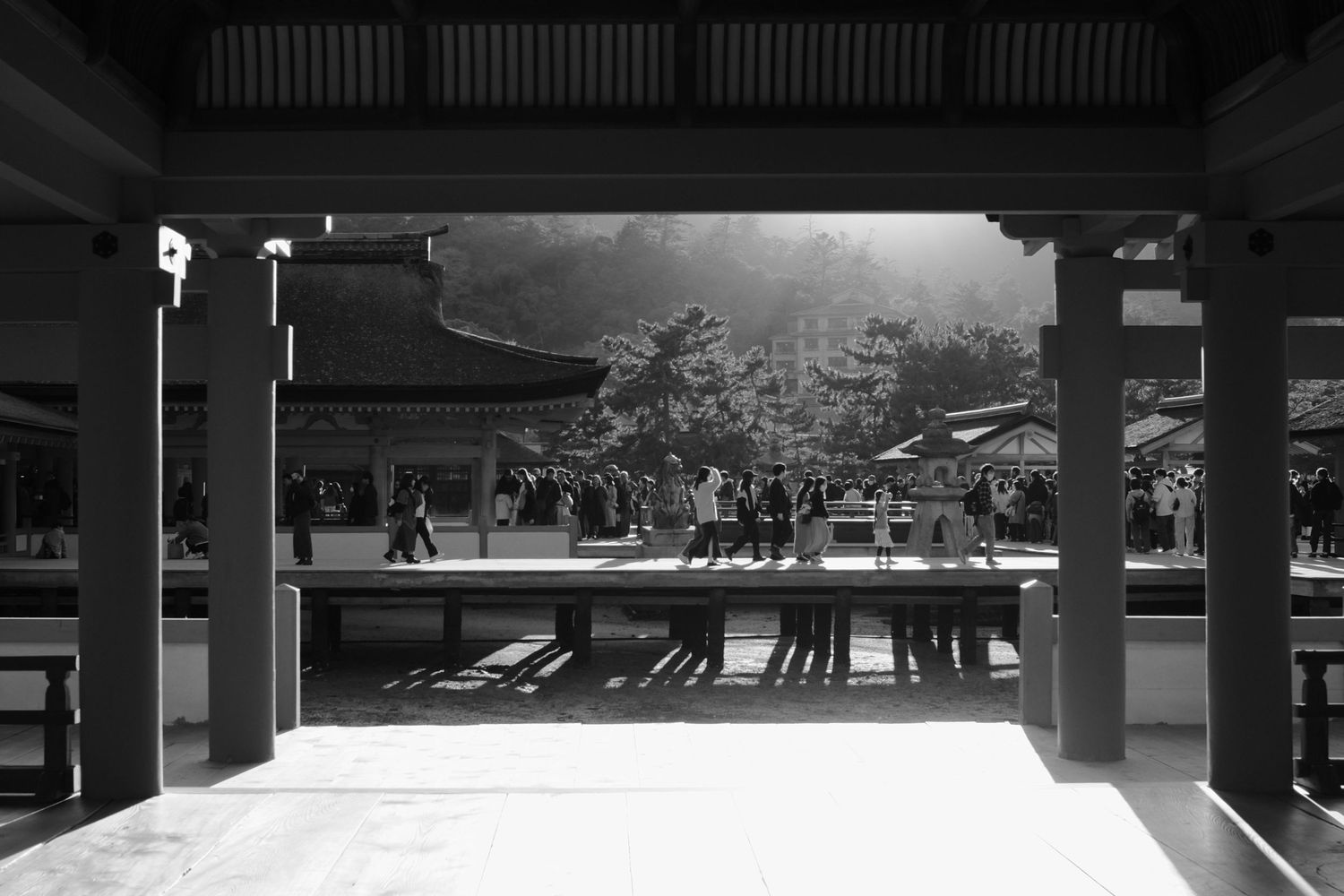 A black and white panoramic photograph shows an empty underground parking garage with concrete pillars and shadows.