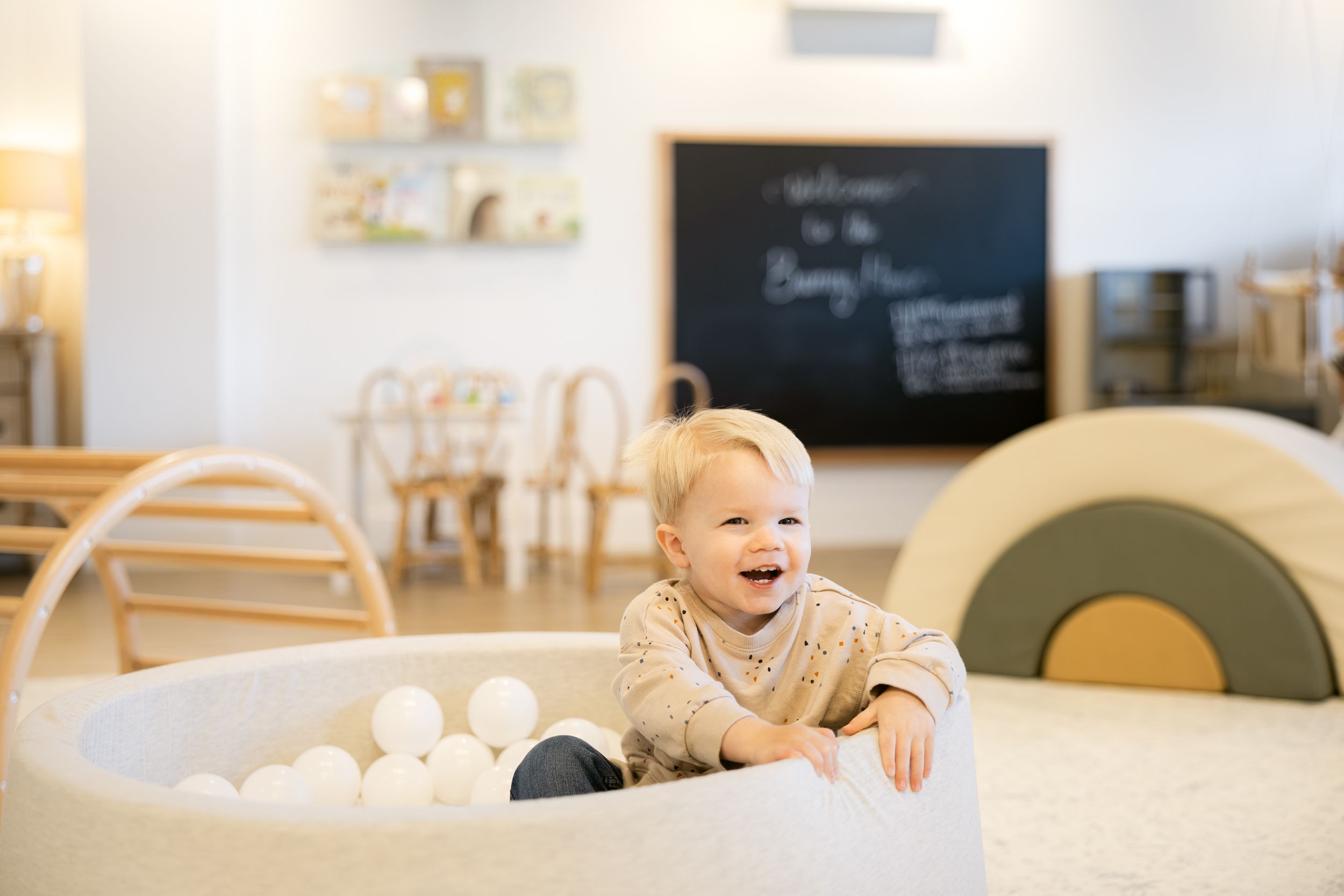 Bright modern nursery room with white furniture and chalkboard wall.