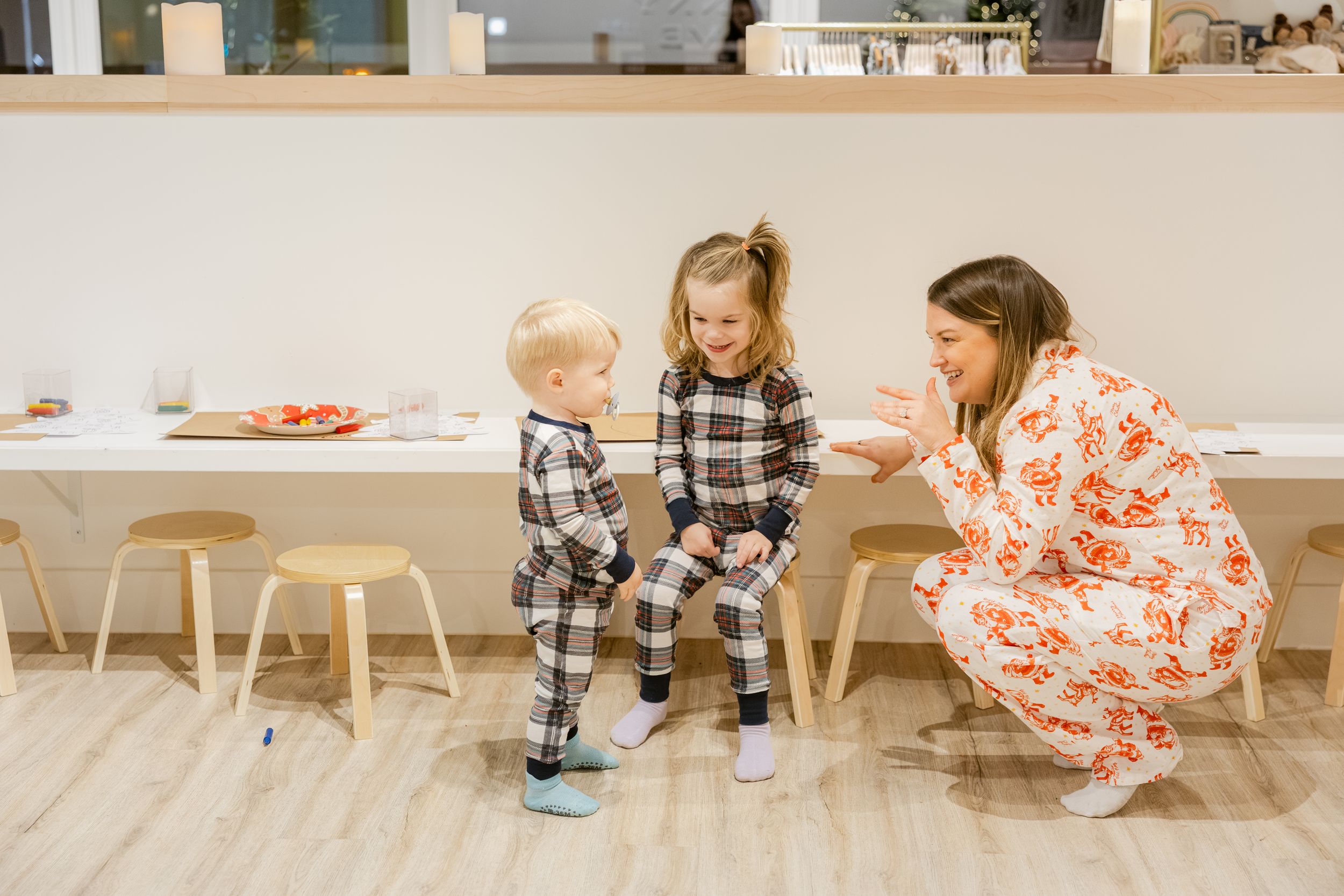 Children sit at a low wooden table in a modern minimalist playroom setting.