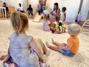 Children sit on a carpeted floor during a group activity at a learning center.