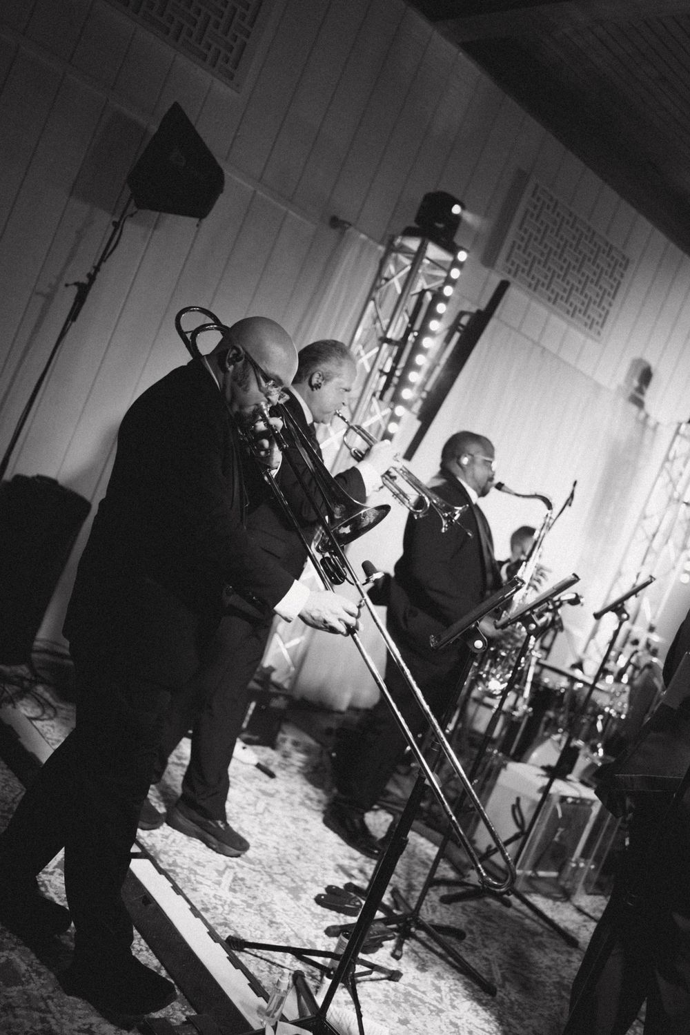 Black and white photo of jazz musicians performing on stage with brass instruments and microphones.