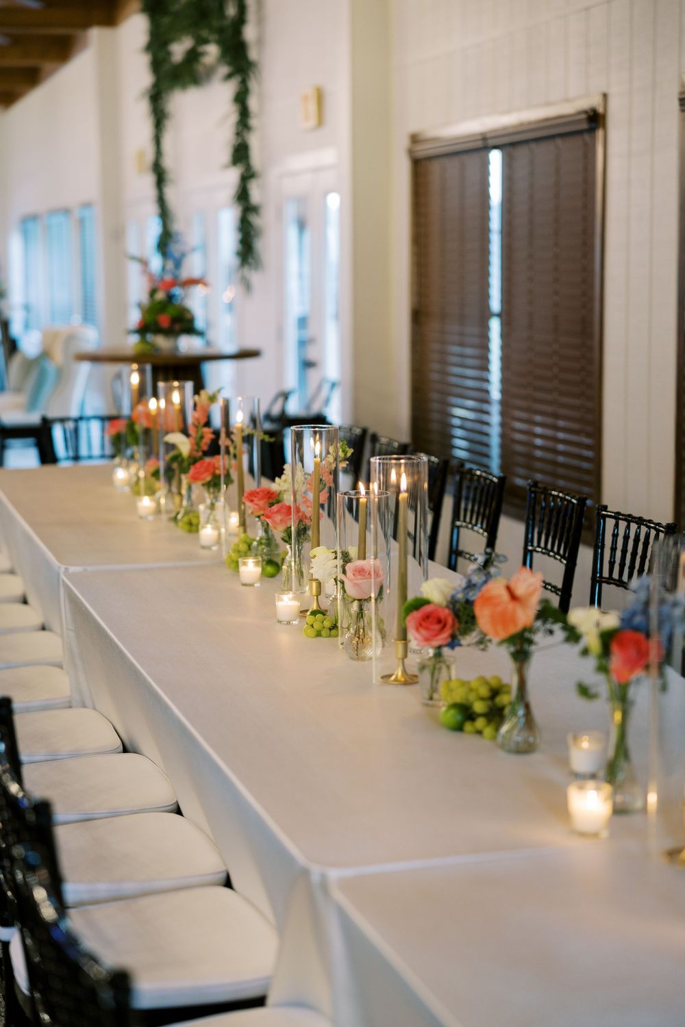 Elegant wedding reception table setting with white linens, candles and coral floral centerpieces.