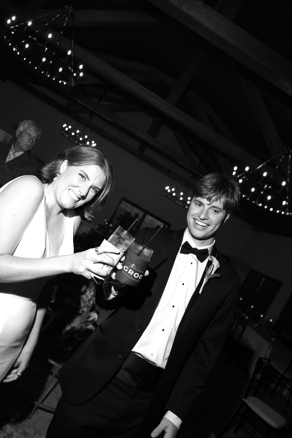 A formal event celebration with guests in black tie attire under string lights.
