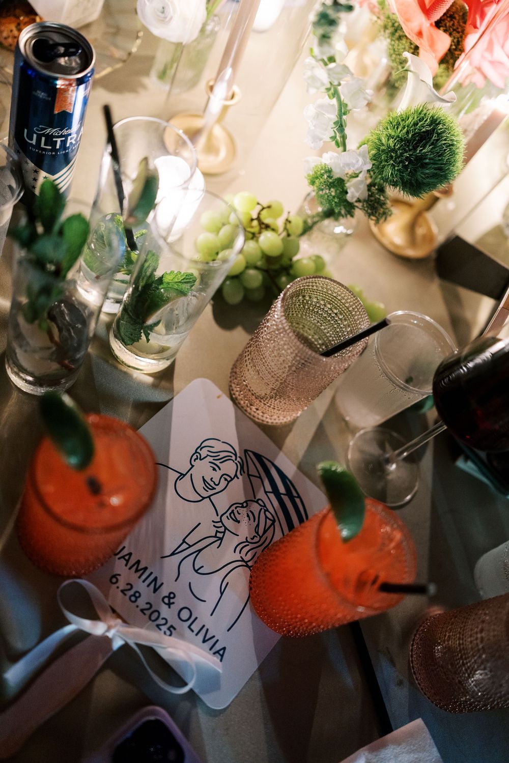 Wedding reception table details with wine bottles, sketched place cards and decorative elements.
