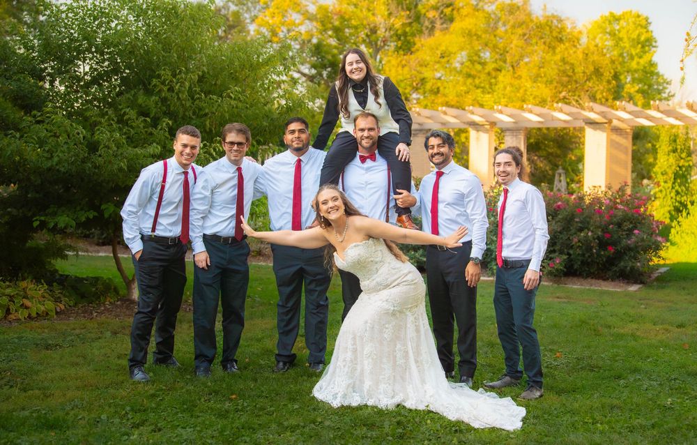 Wedding party poses together in a garden setting with autumn foliage creating a warm golden backdrop. Quad Cities Wedding Photography
