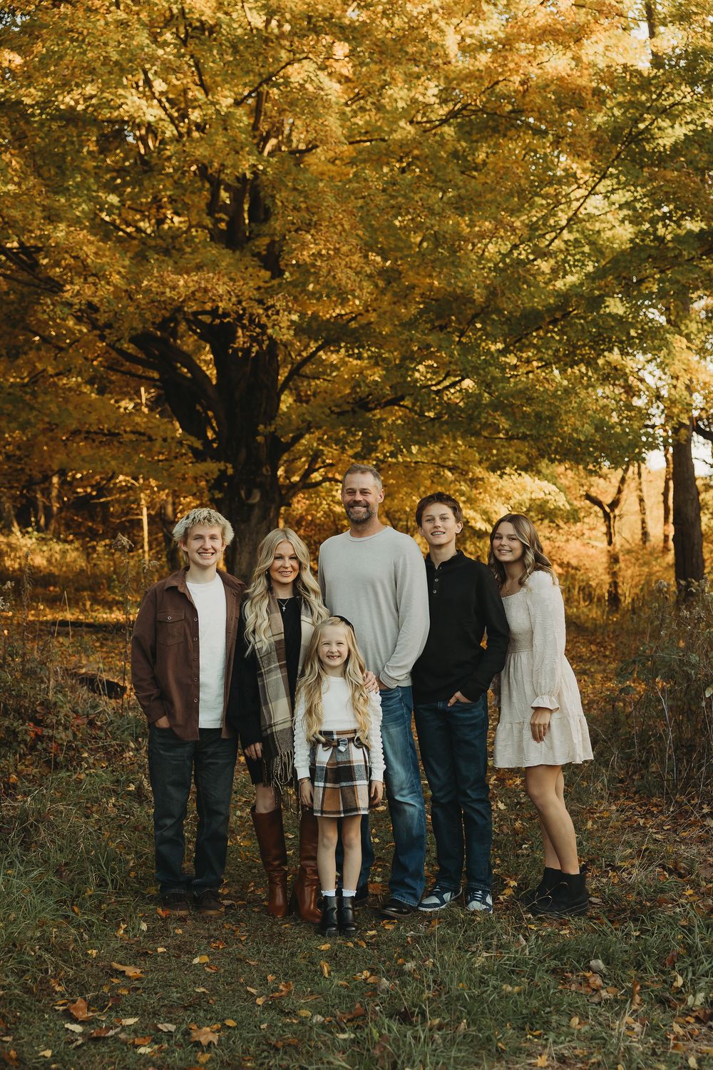 A group poses together in a wooded area during autumn with golden leaves and natural lighting.