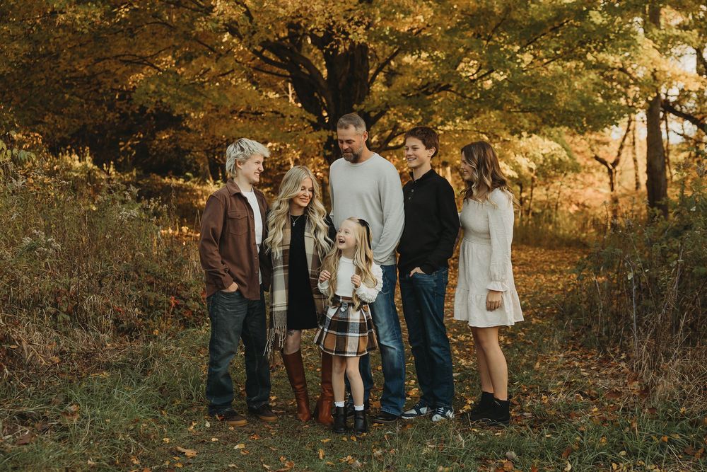 A group of people standing together in a wooded area during golden hour lighting.