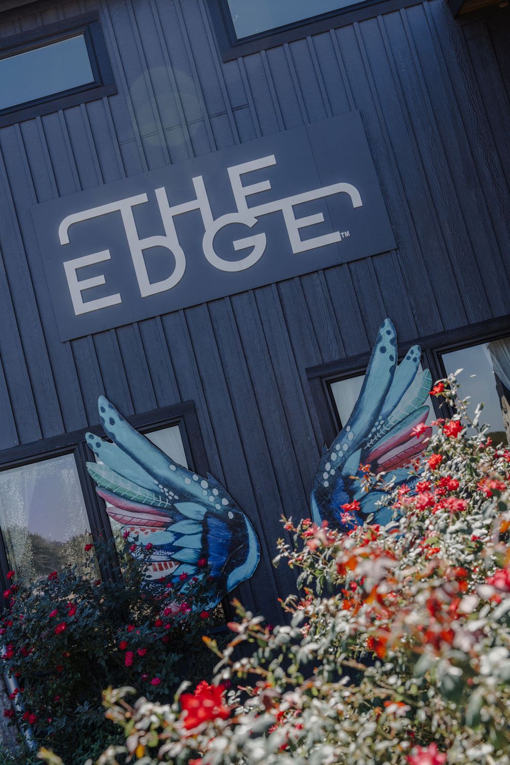 Modern building exterior with 'THE EDGE' signage and colorful flower garden.