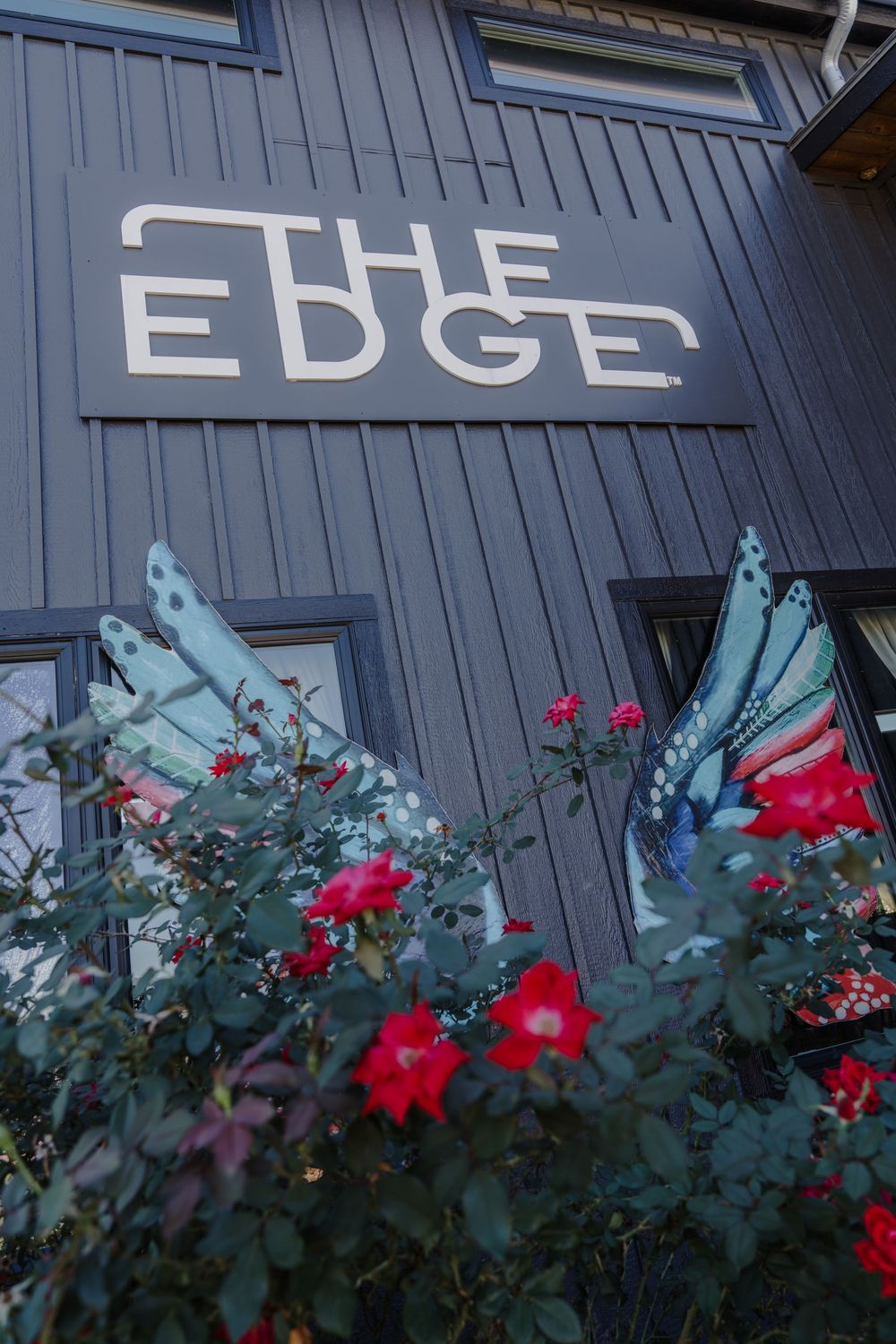 Modern building facade with 'EDGE' signage and bright red flowers blooming below.