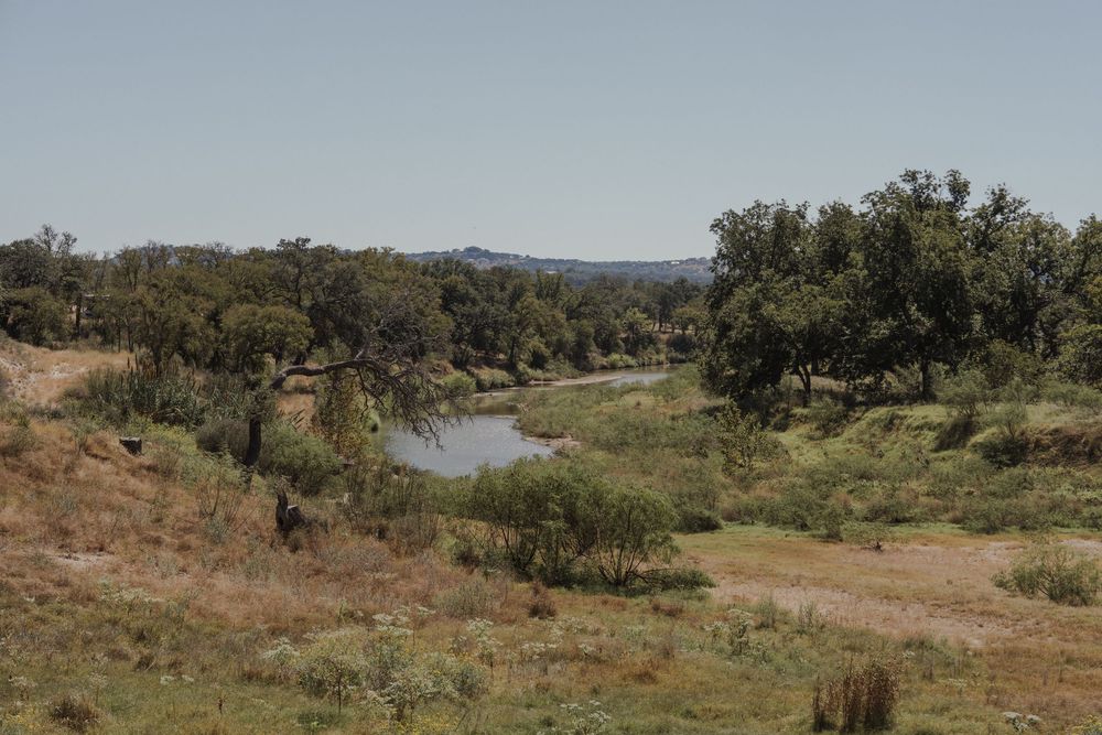 Scenic countryside landscape with trees and winding river in distance.