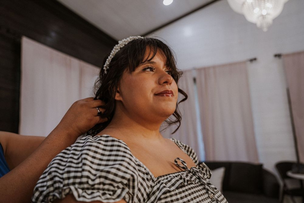 A person wearing a black and white gingham dress sits at a table during wedding preparations.