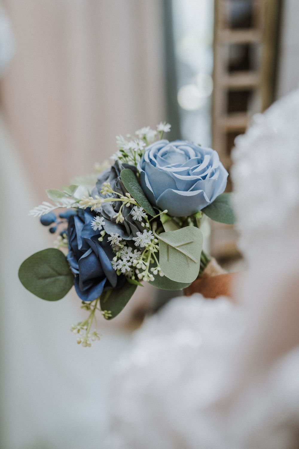 Light blue roses and greenery arranged in a delicate wedding bouquet with soft focus.