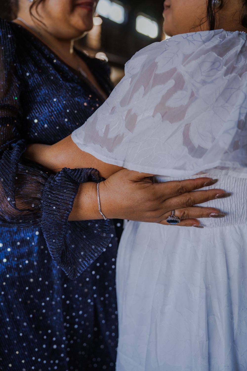 Close-up detail of hands adjusting white wedding dress fabric.