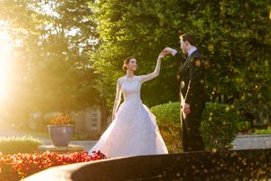 Bride and groom share a romantic moment in golden sunlight surrounded by lush garden greenery and flowers.