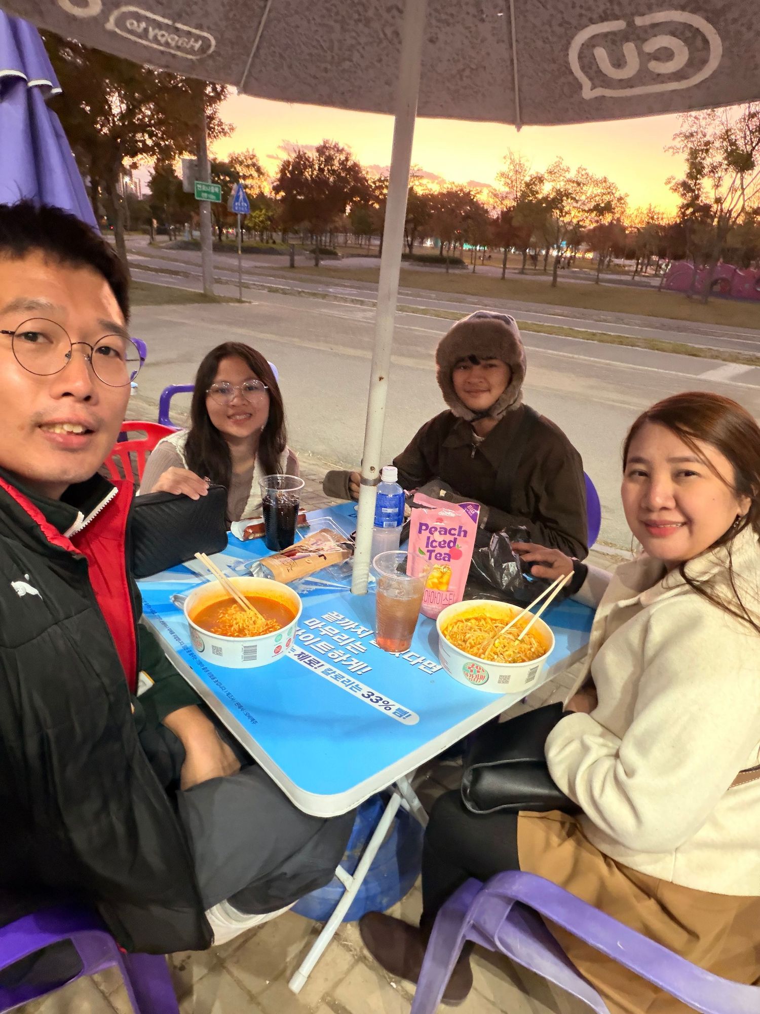 A group of friends enjoying snacks and drinks together at an outdoor table during sunset.