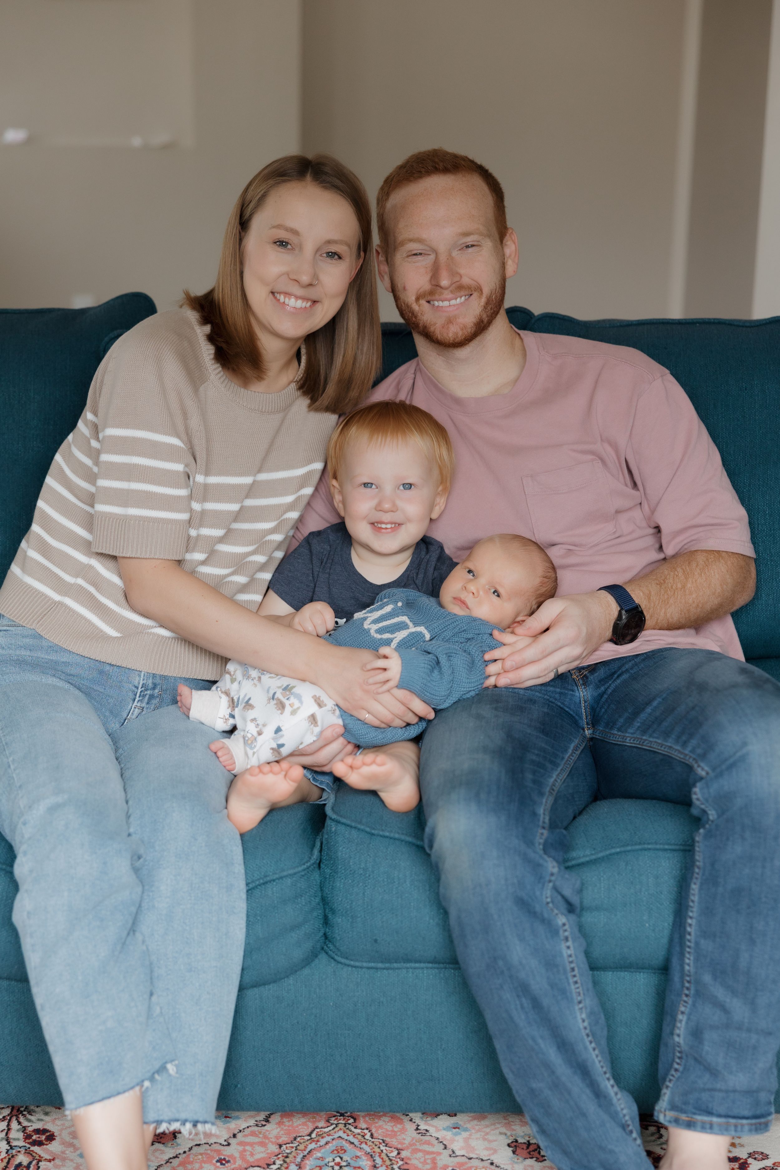 Family relaxes together on blue couch during casual home photo session.