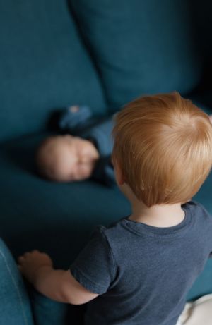 Close-up view of toddler in grey shirt sitting on blue couch.