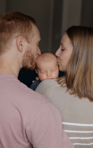 Intimate family portrait series showing parents sharing loving moments with their baby.