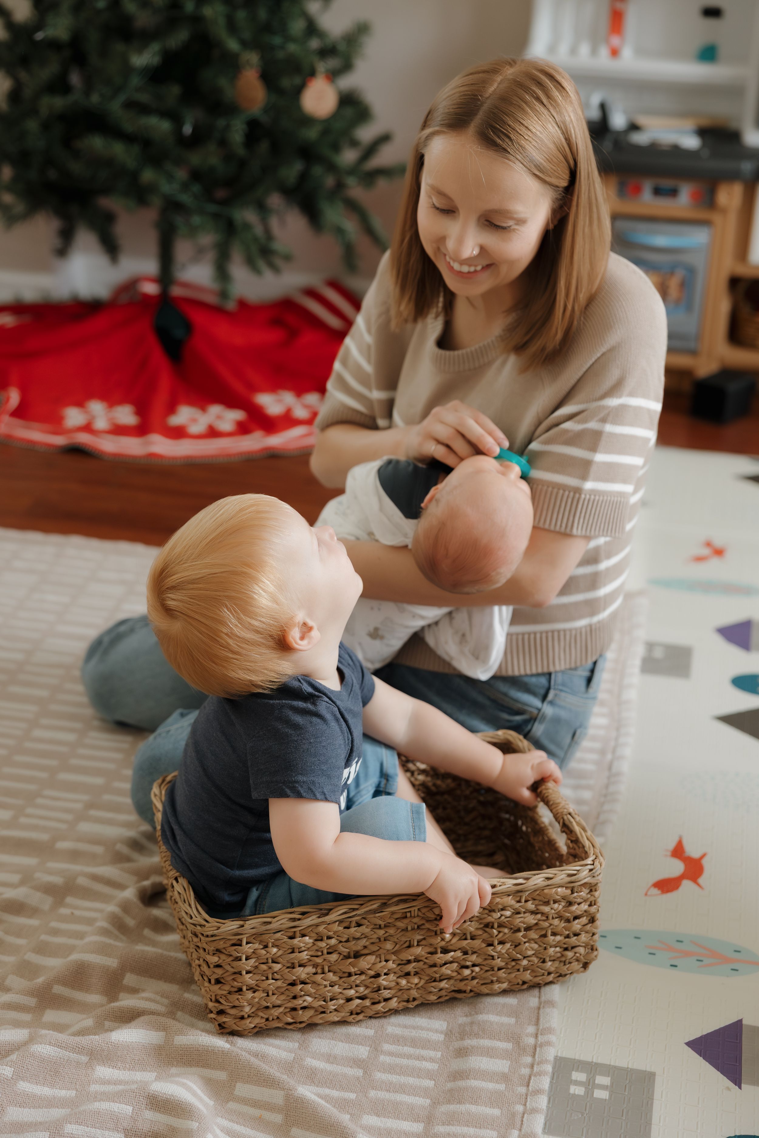 Baby in blue outfit plays in woven basket during indoor photoshoot.