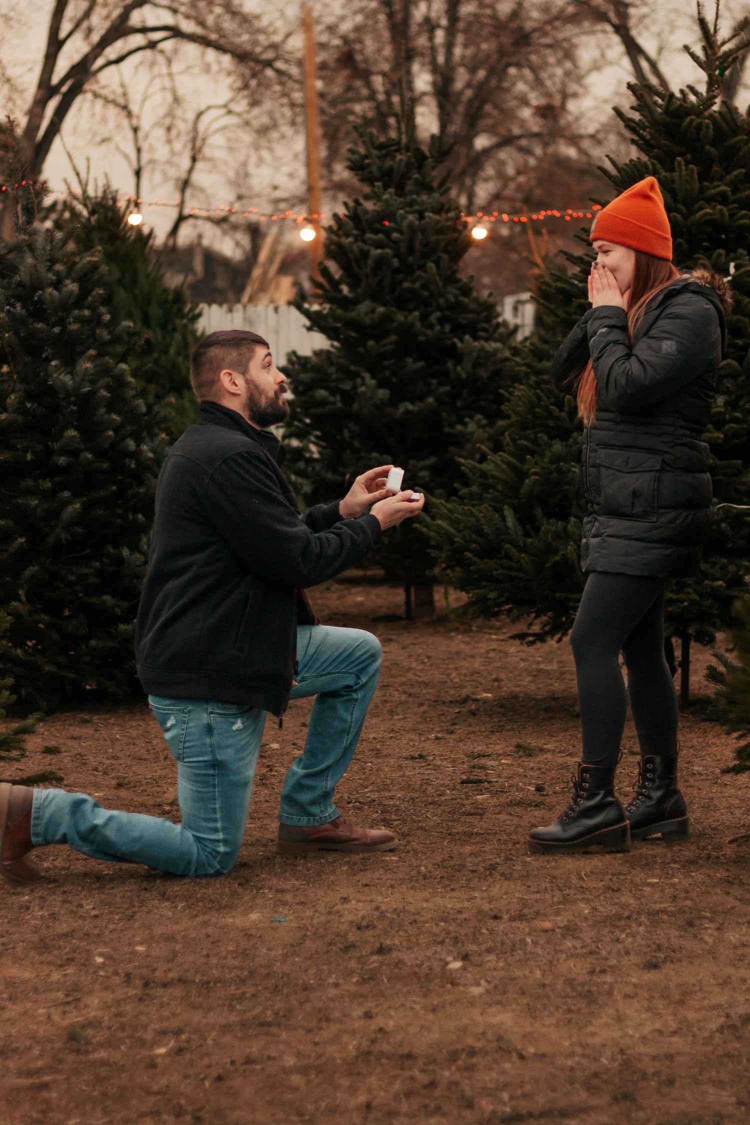 Man proposes to woman wearing orange beanie at a Christmas tree farm | Westminster Colorado Proposal Photographer