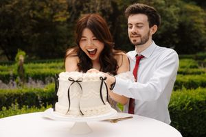 A couple in formal attire shares a joyful moment together in a lush garden setting.
